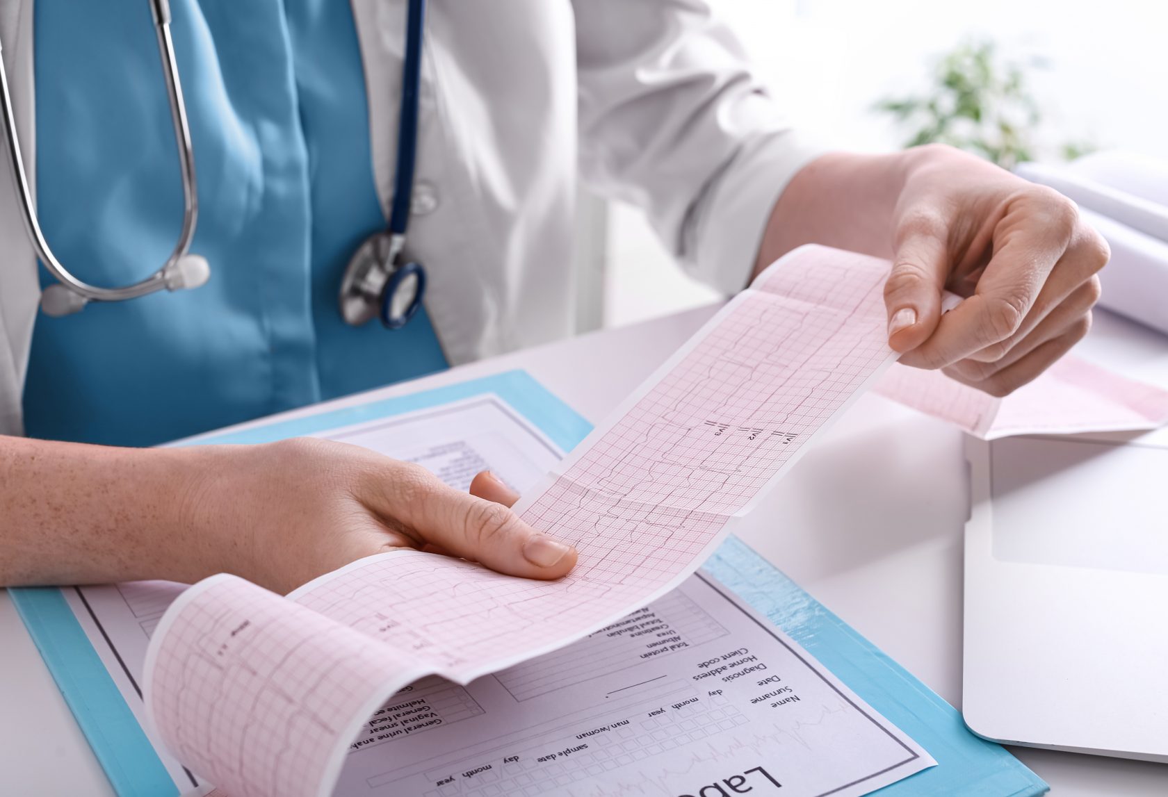 Doctor examining cardiogram at table in clinic, closeup