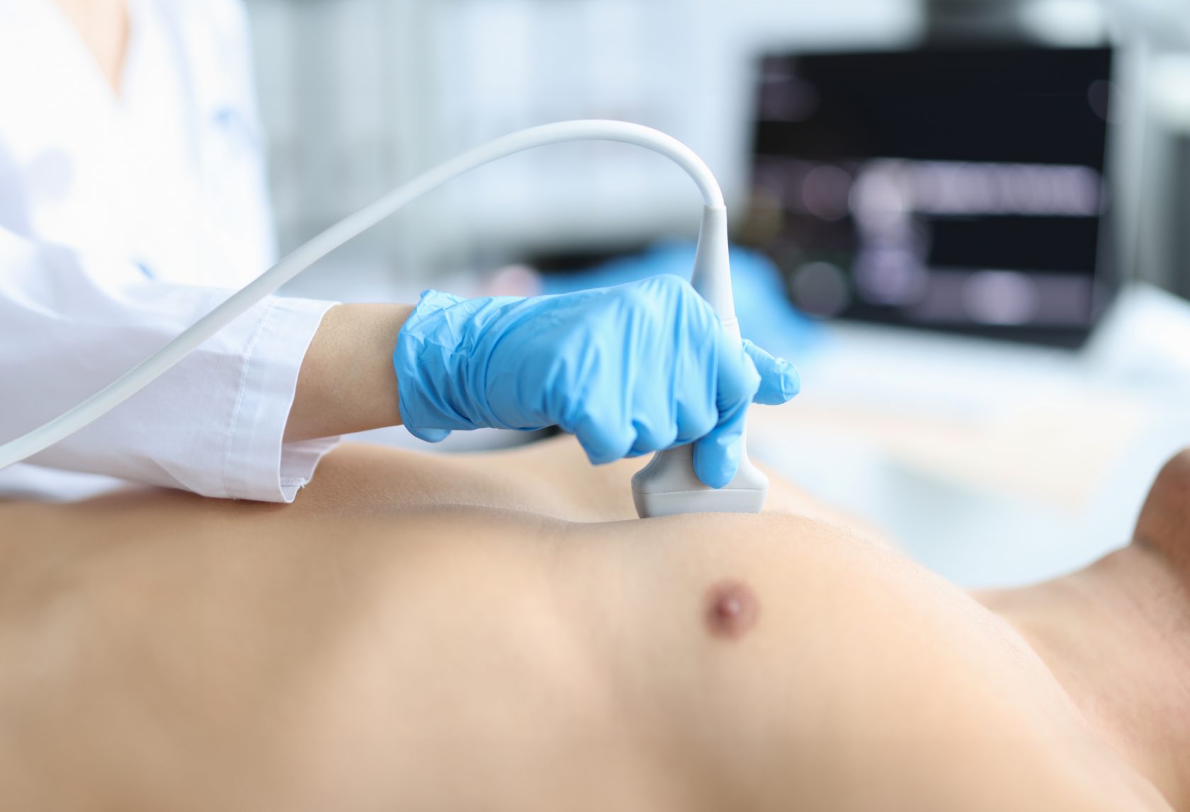 Doctor makes echocardiography of male patient using ultrasound probe pressing on patient chest